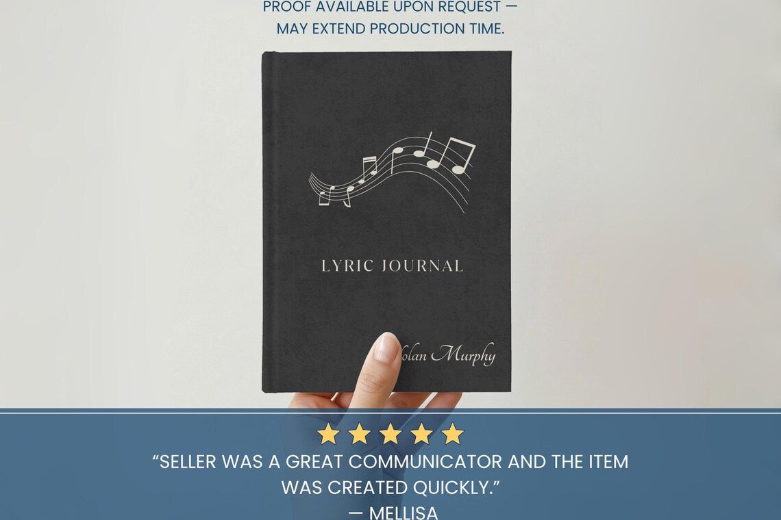 A hand holding a black lyric journal with white musical notes and the title 'LYRIC JOURNAL' on the cover, set against a light background with promotional text banners above and below.